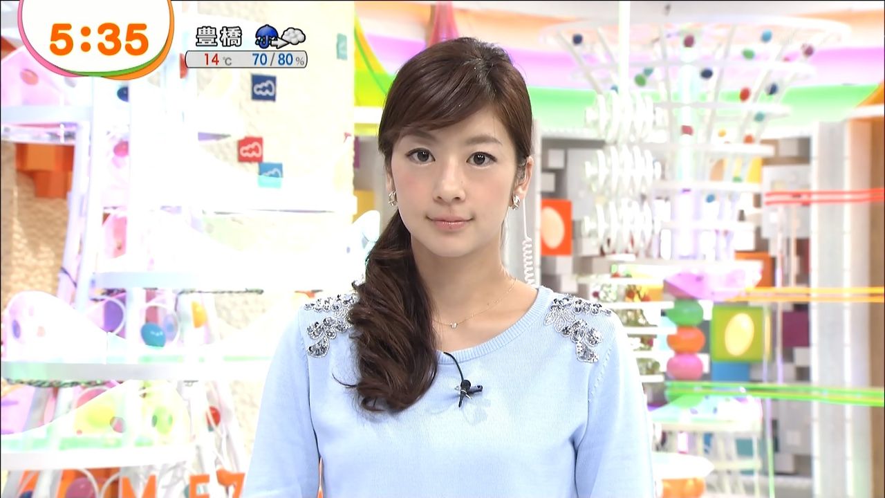 ビジュー付きの水色のセーターを着てカメラを見つめるアナウンサー、生野陽子