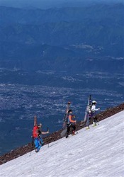 スキーを背負って7合目付近の斜面を登る登山者