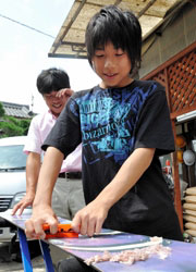 父親の義幸さん(奥)とスノーボードの手入れをする今井郁海君