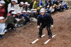 落ち葉の上を元気よく滑走する児童