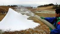 ホースから勢いよく吹き出し、山のように積もる人工雪(高島市今津町・箱館山スキー場)