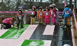 雪のない人工芝の坂道で滑り降りる練習をする子供たち=11日、長野県軽井沢町の軽井沢プリンスホテルスキー場(村島有紀撮影)
