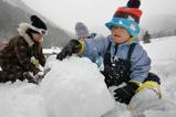 再オープンしたゲレンデで雪だるまを作って遊ぶ親子