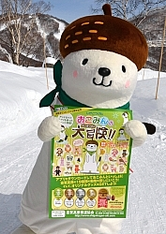 新企画のポスターを持つ志賀高原のPRキャラクター「おこみん」