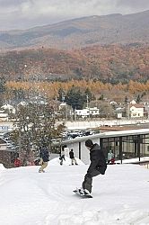 紅葉に向かってゲレンデを滑り降りるスノーボーダー