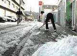 市街地では今冬初めての積雪となり、雪かきをする住民