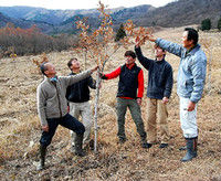 ゲレンデ跡に植樹したクヌギの成長を見守る今森さん(左)と住民たち(昨年12月、高島市マキノ町・マキノスキー場)