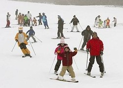 時折、雪が舞うゲレンデで初滑りを楽しむ人たち=18日午前9時32分、愛知県豊根村の茶臼山高原スキー場で
