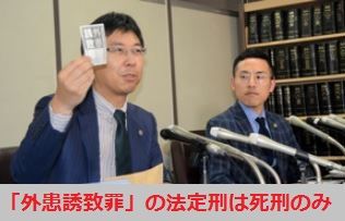 「外患誘致罪」と書かれた紙片をかざす佐々木弁護士