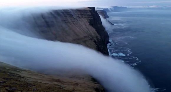 ミラクル自然現象。霧が滝のように海に流れ込む黙示録的世界