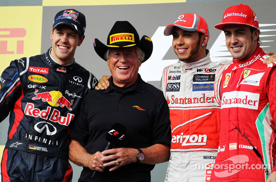 2012年F1アメリカGP 1位ルイス・ハミルトン(マクラーレン)、2位セバスチャン・ベッテル(レッドブル)、3位フェルナンド・アロンソ(フェラーリ)と表彰台インタビュアーのマリオ・アンドレッティ