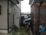 住宅の間に突っ込んだ軽自動車