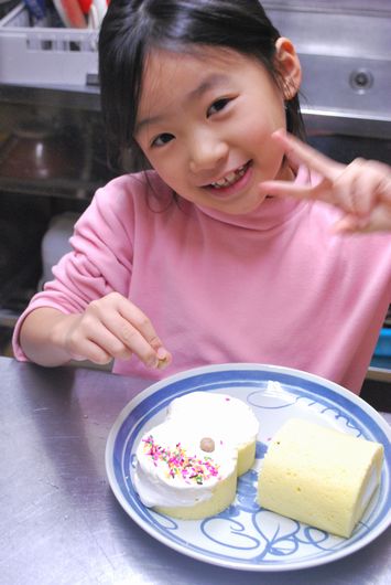 ロールケーキをデコレーションする女子小学生