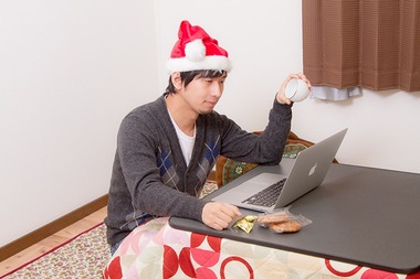 サンタ帽をかぶってコタツに入る男性