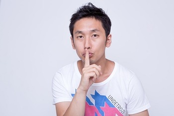 内緒のポーズをする男