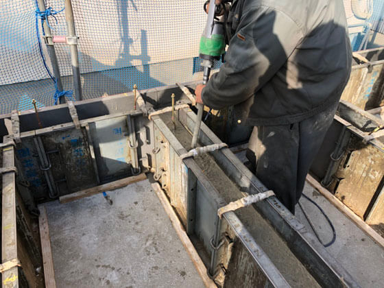 型枠の中にまんべんなくコンクリート充填。コンクリート内にバイブレータを挿入してコンクリートの締固めを行います。