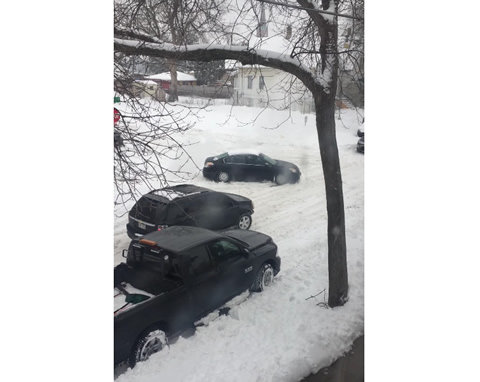 Stuck Car Struggles on Snowy Street