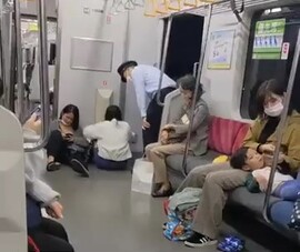 電車内のコンセントでスマホを充電する女性