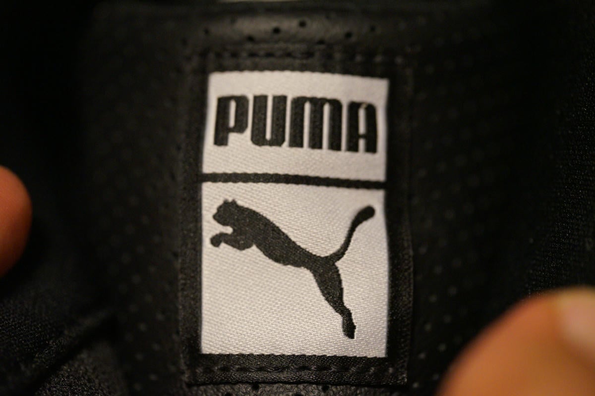 シュータンロゴは刺繍。黒の縁取りのホワイトタグに黒の刺繍でPUMAの文字とプーマキャットを刺繍している。