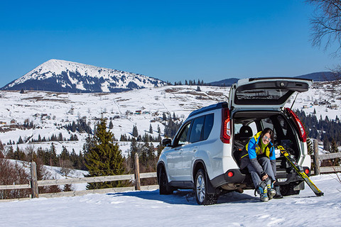 woman-changing-boots-to-ski-sitting-in-car-trunk.-sunny-day