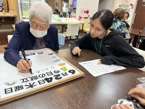 スタッフと入居者が一緒に文字や絵を描く制作活動の様子