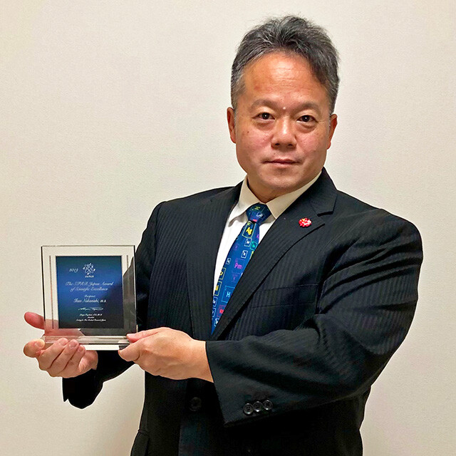 Dr. MaCHO Holding the Award Plaque