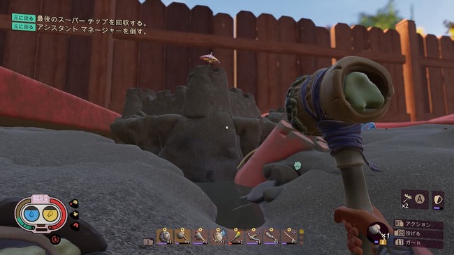 ハンマーを手に庭の砂場エリアにある巨大な砂の城を眺めているマックス