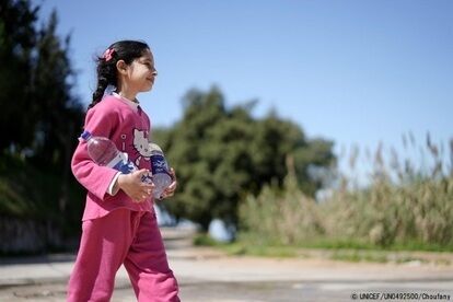水の入ったペットボトルを持って歩く10歳のシリンさん。家族のために、毎日父親と一緒に水を汲んで自宅まで運んでいる。(2021年3月撮影) (C) UNICEF_UN0492500_houfany