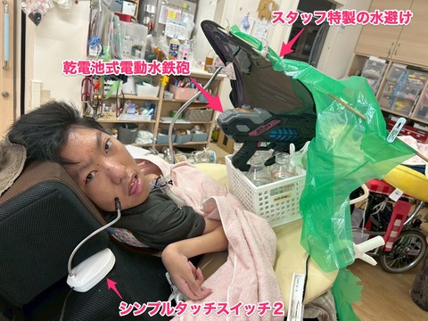 シンプルタッチスイッチ2に入力して電動水鉄砲で水をかけるRさん&スタッフ特製水避け