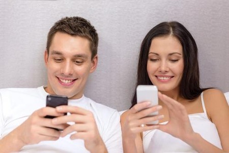 happy-couple-bed-using-smartphones