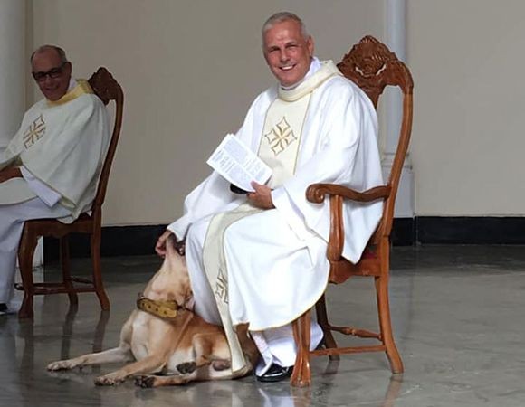 聖職者が好きすぎる犬。ミサの最中に壇上に上がり神父さんの足元でジャレジャレ（ブラジル）