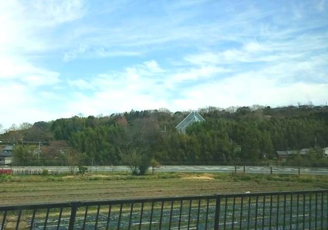 バスでくろまろの郷へ。畑の向こうに花の文化園の大温室が見えてきた