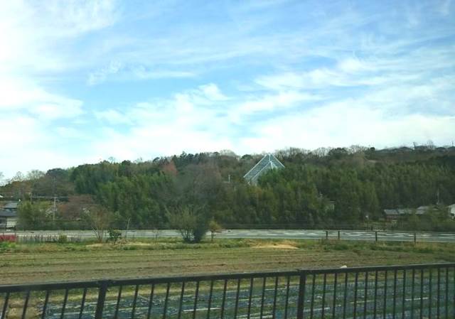 バスでくろまろの郷へ。畑の向こうに花の文化園の大温室が見えてきた