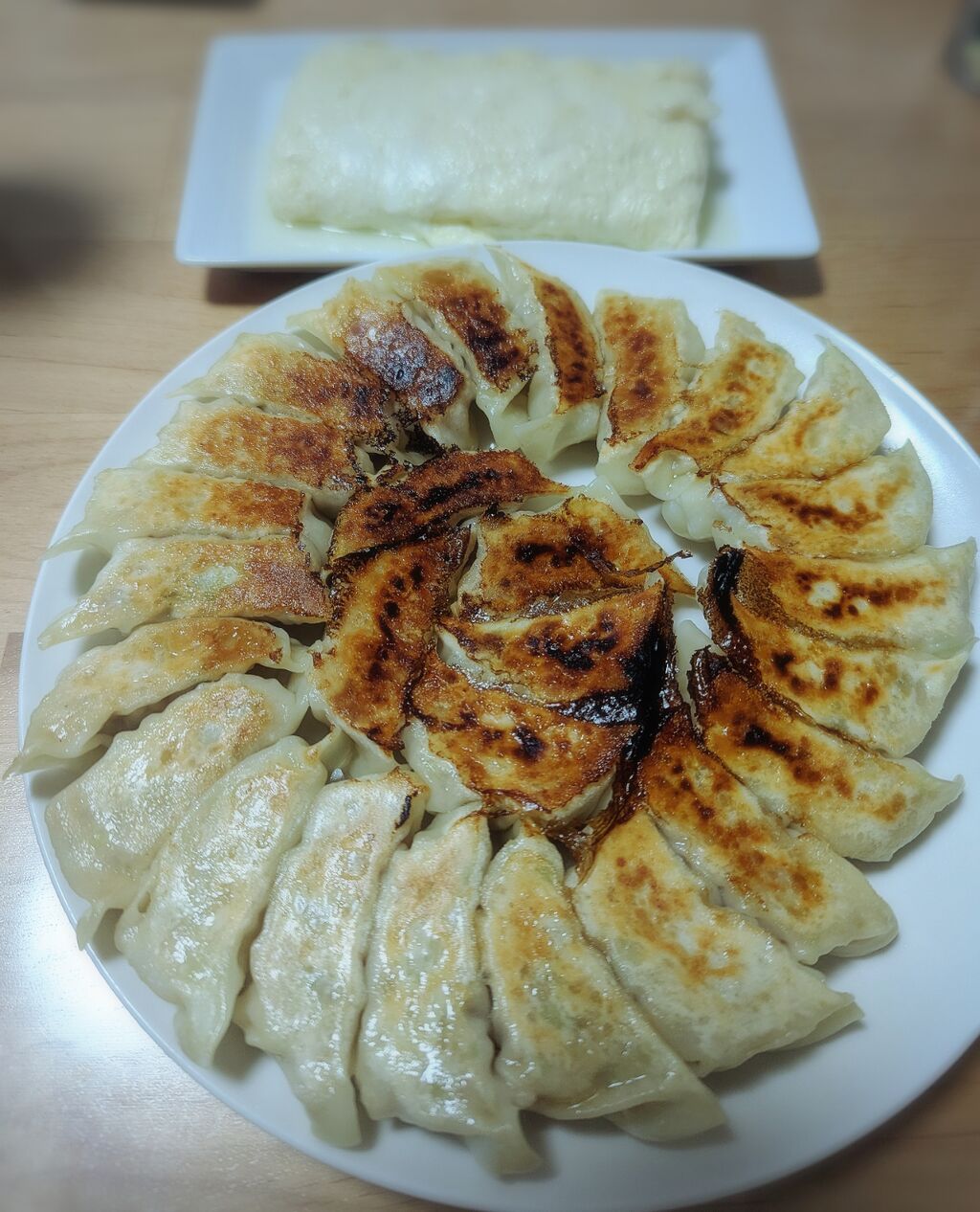 焼き目が美しい手作り餃子が大皿にぐるりと並んでいる様子
