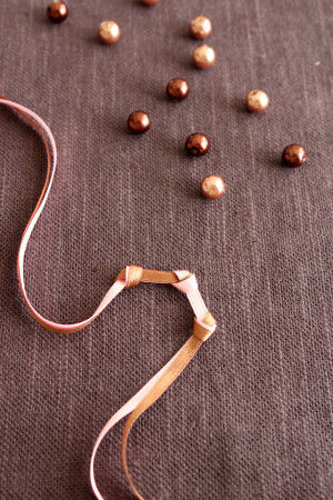 1つ目の結び目のかさなりの色と交互になるように、次の結びめを作る。この時ビーズの幅をあけて結んでください。くりかえして、先に結び目だけのブレスレットを作ります。