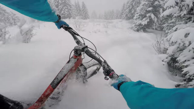 雪深く埋もれたダウンヒルコースを強引に走る、マウンテンバイクのライダー視点映像