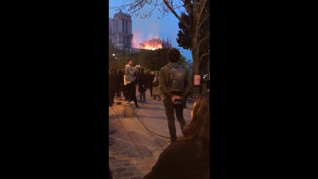 火災で燃え落ちるノートルダム大聖堂。その光景を見つめながら聖歌を歌うパリの人々