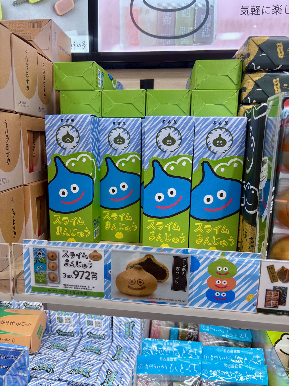お店の棚に縦に並んでる「スライムまんじゅう」の細長い箱、箱には青いスライムのイラスト