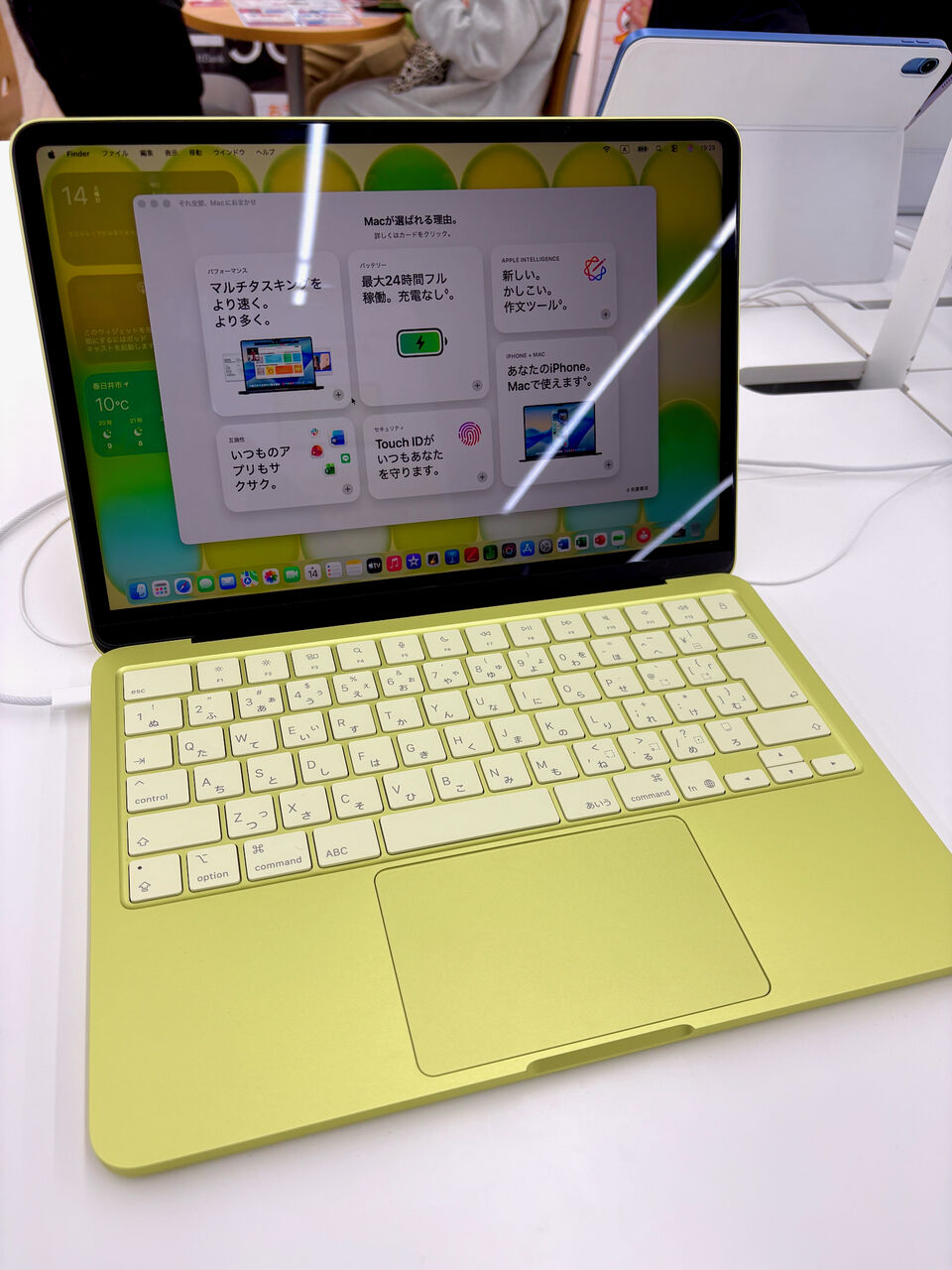 メタリックなライトグリーンな本体の Macbook Neoの店頭展示機、画面には本体の説明アプリが起動してる、キーボードもうっすらライトグリーン