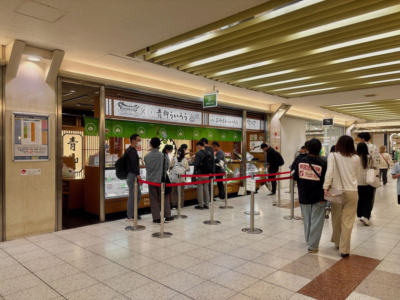 地下街青柳ういろう直営店の前に数人のお客、そしてお店の前には赤いゴムとそれをささえる金属の低い柱が行列を効率良く並ばせるために蛇行して並べてある