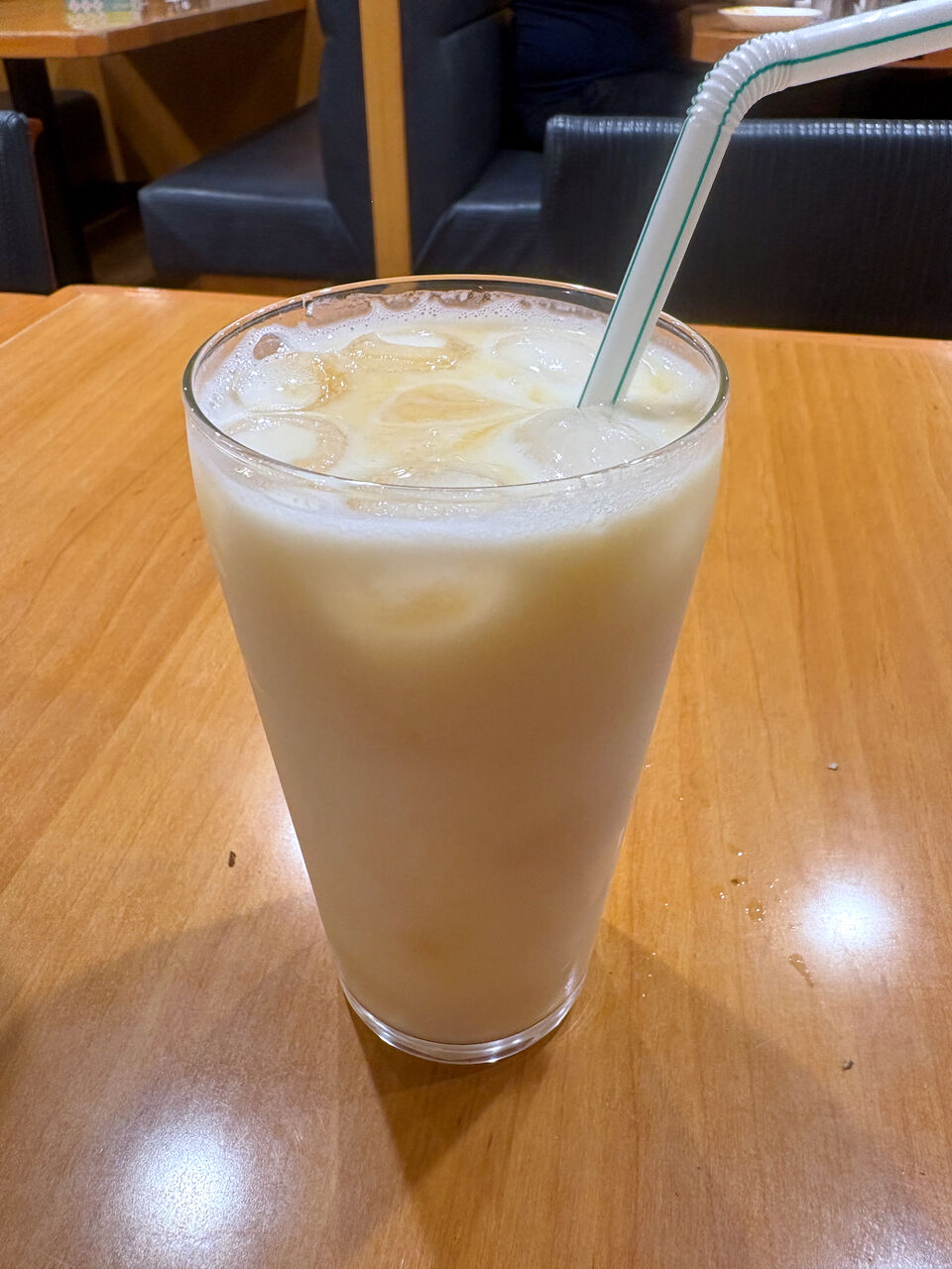 氷入りグラスに入ってるマンゴーラッシー。ストローがささってる。