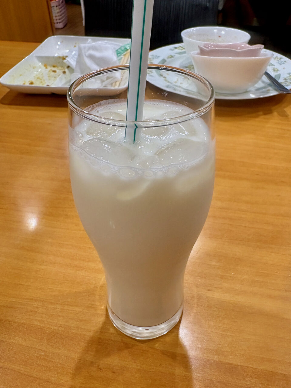 氷が入ったグラスに入れられてるラッシーに白いストローがささってる。ぱっと見、氷入り牛乳のよう。