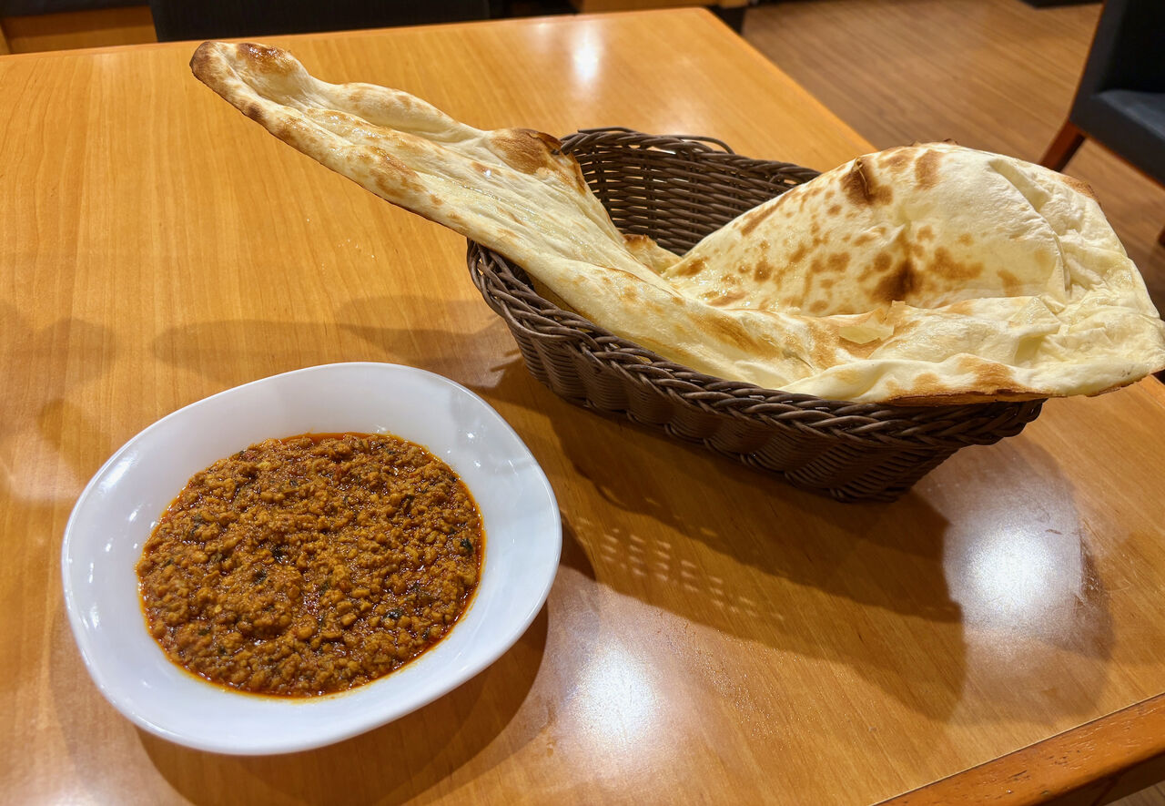 白い小皿に入ったキーマカレーと、細い枝で編まれたバスケットの中に入れられてるでっかいナン