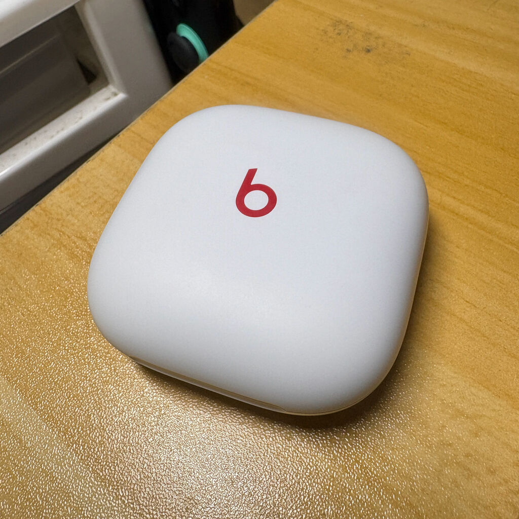Beats Fit Pro のケース。ケースの色は白色でフタの真ん中に赤字で「b」のマーク。