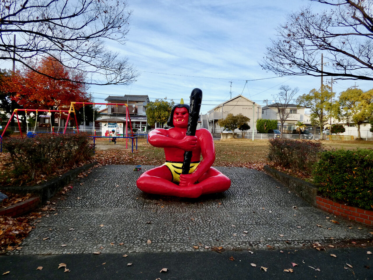 公園の入り口の中央に、金棒を右手に持ち胸を張って座る赤鬼の像。
