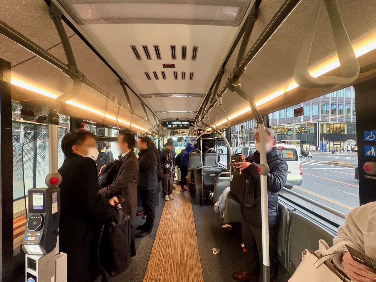 前側車両の車内を車両中央から撮影。数人が立って乗ってるがかなり空きスペースあり。