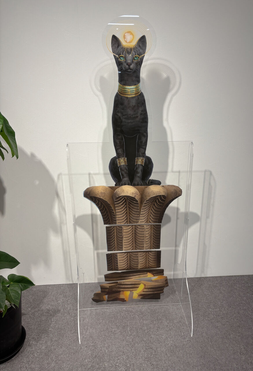 金色の台座の上に金色の首輪をした青い目の大きな黒猫が座ってる、頭の上には金色の球状なものが光ってる