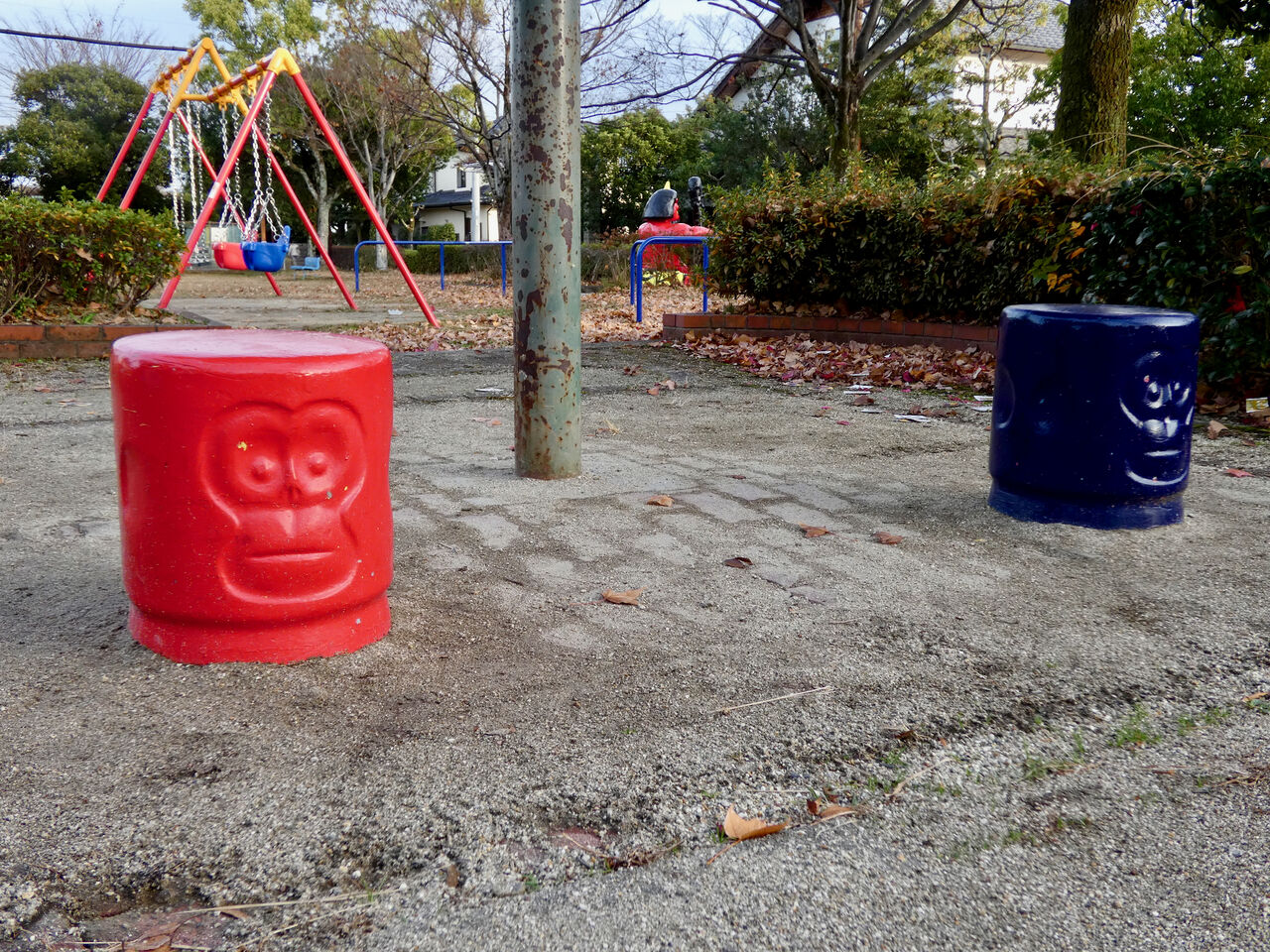公園にある円柱状の椅子。赤色と青色があり、両方側面に猿の顔が。