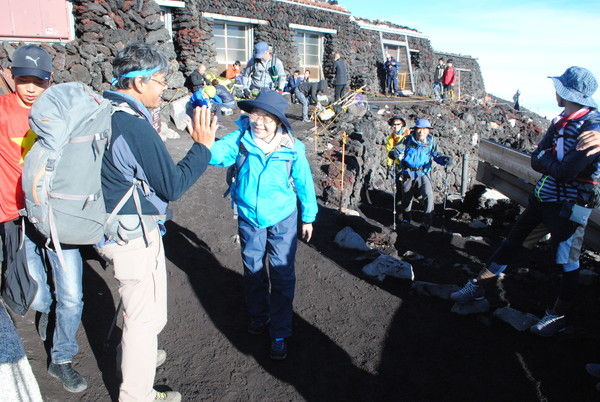 山頂で太田ガイドとハイタッチする参加者
