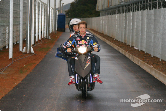 ヴェッテル、マーシャルを乗せてバイクを運転してピットに